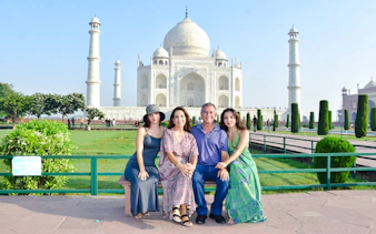Family sitting in front of the Taj Mahal during sunrise tour in Agra.