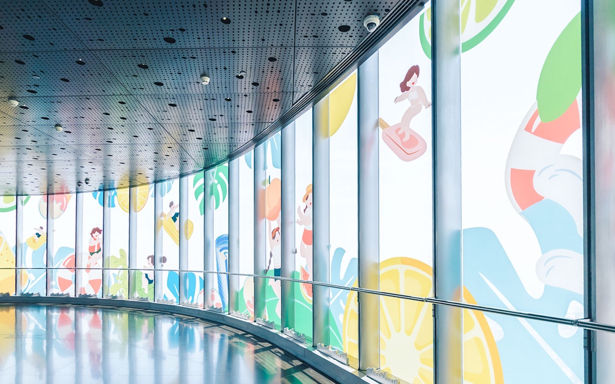 Curved hallway in Shanghai Tower with colorful window decorations.