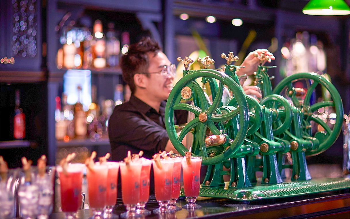Bartender using vintage machine to prepare drinks at a Singapore bar.