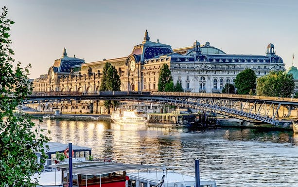 Seine River cruise boat near Musée d'Orsay in Paris at sunset.