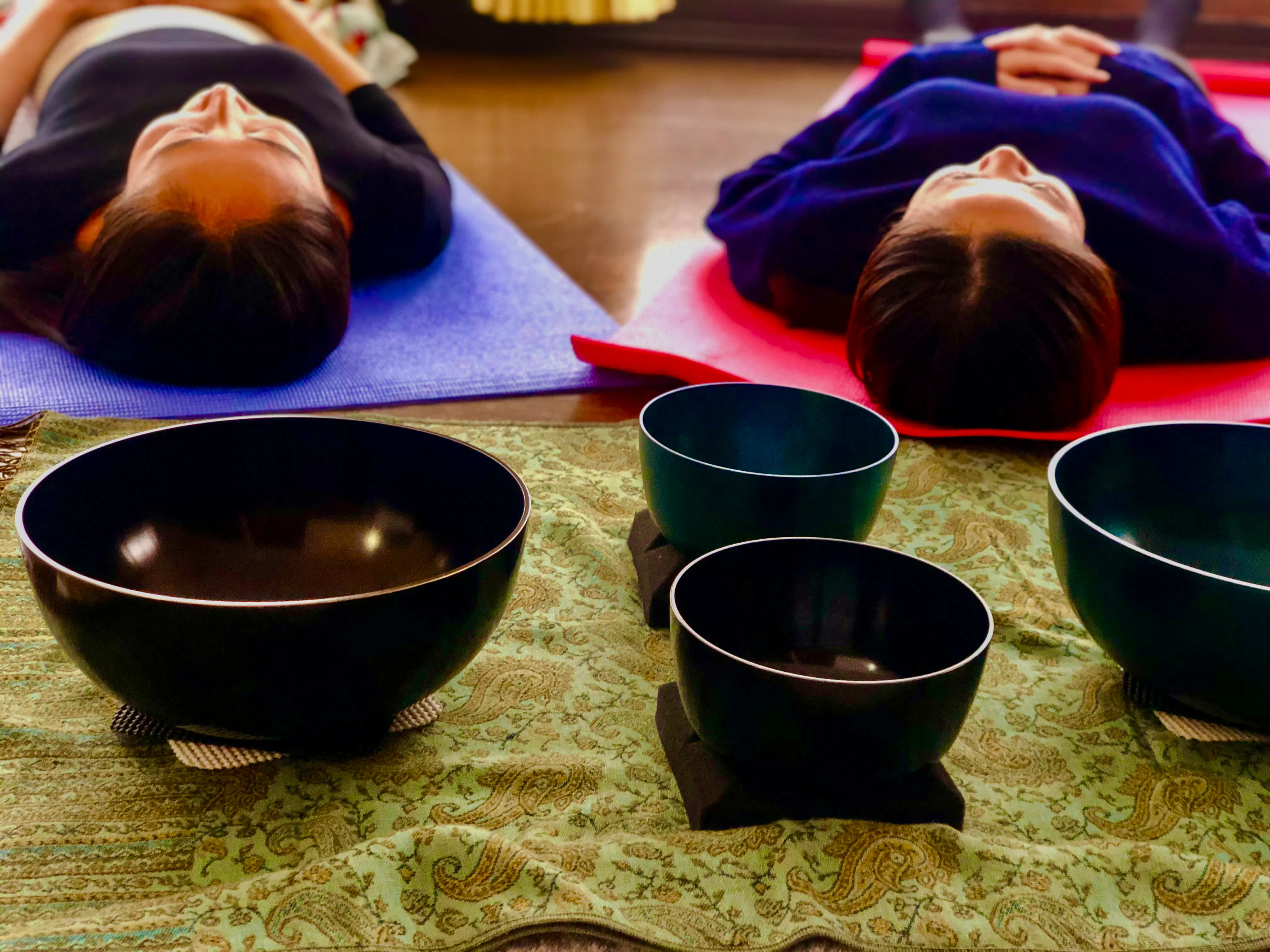 Participants lying on mats during a sound bath meditation with singing bowls in Kyoto.