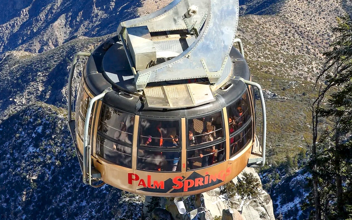 Palm Springs Aerial Tramway car ascending over mountainous landscape.