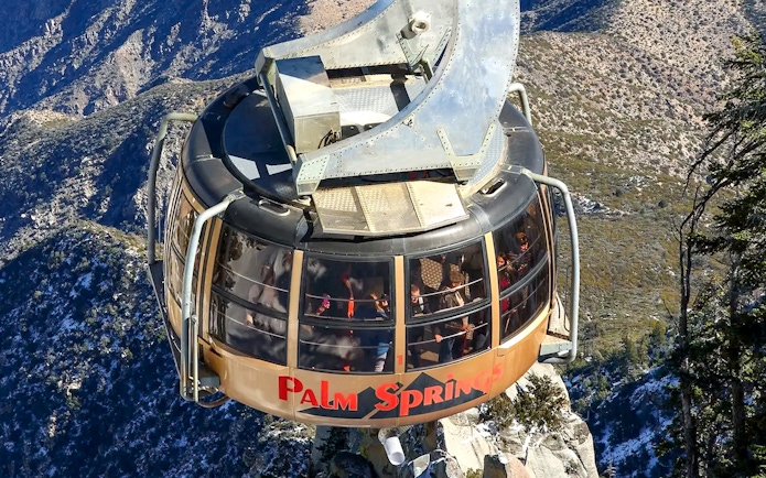 Palm Springs Aerial Tramway car ascending over mountainous landscape.