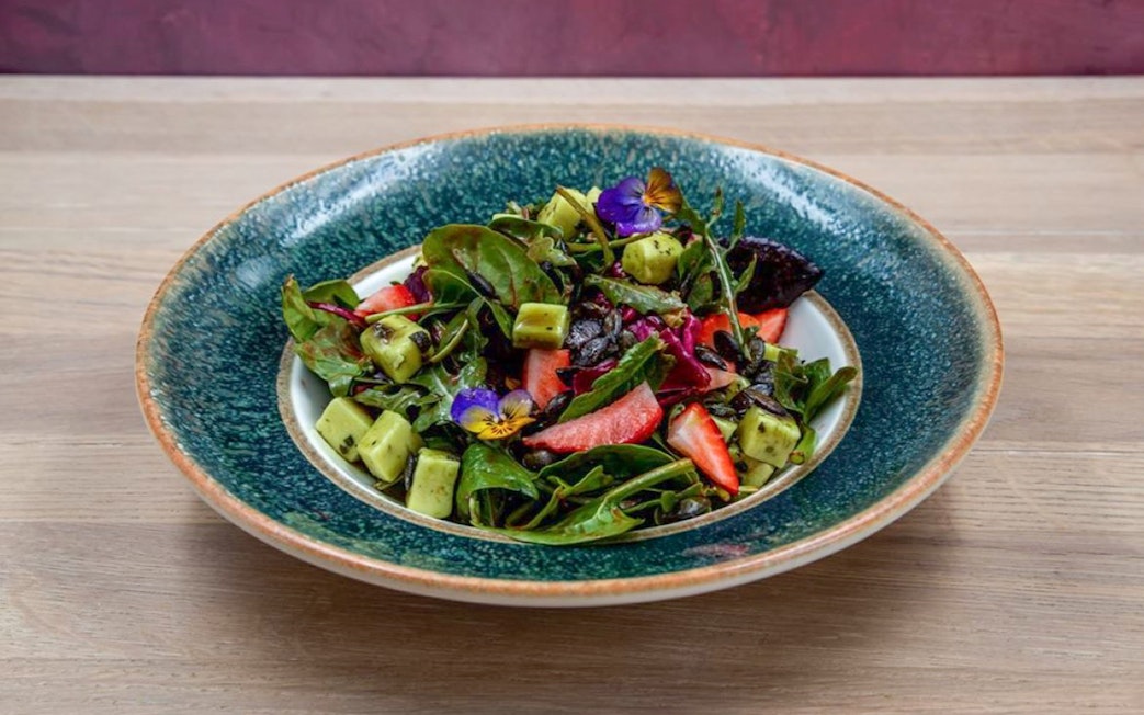 Fresh salad with greens, strawberries, and edible flowers served at Hungarian Royal Guard exhibition in Budapest.