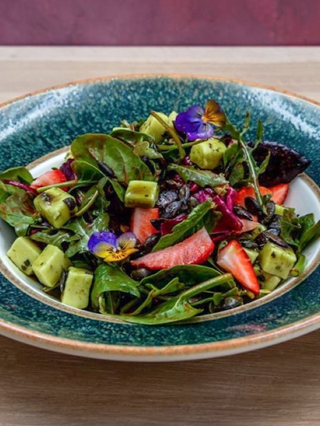 Fresh salad with greens, strawberries, and edible flowers served at Hungarian Royal Guard exhibition in Budapest.