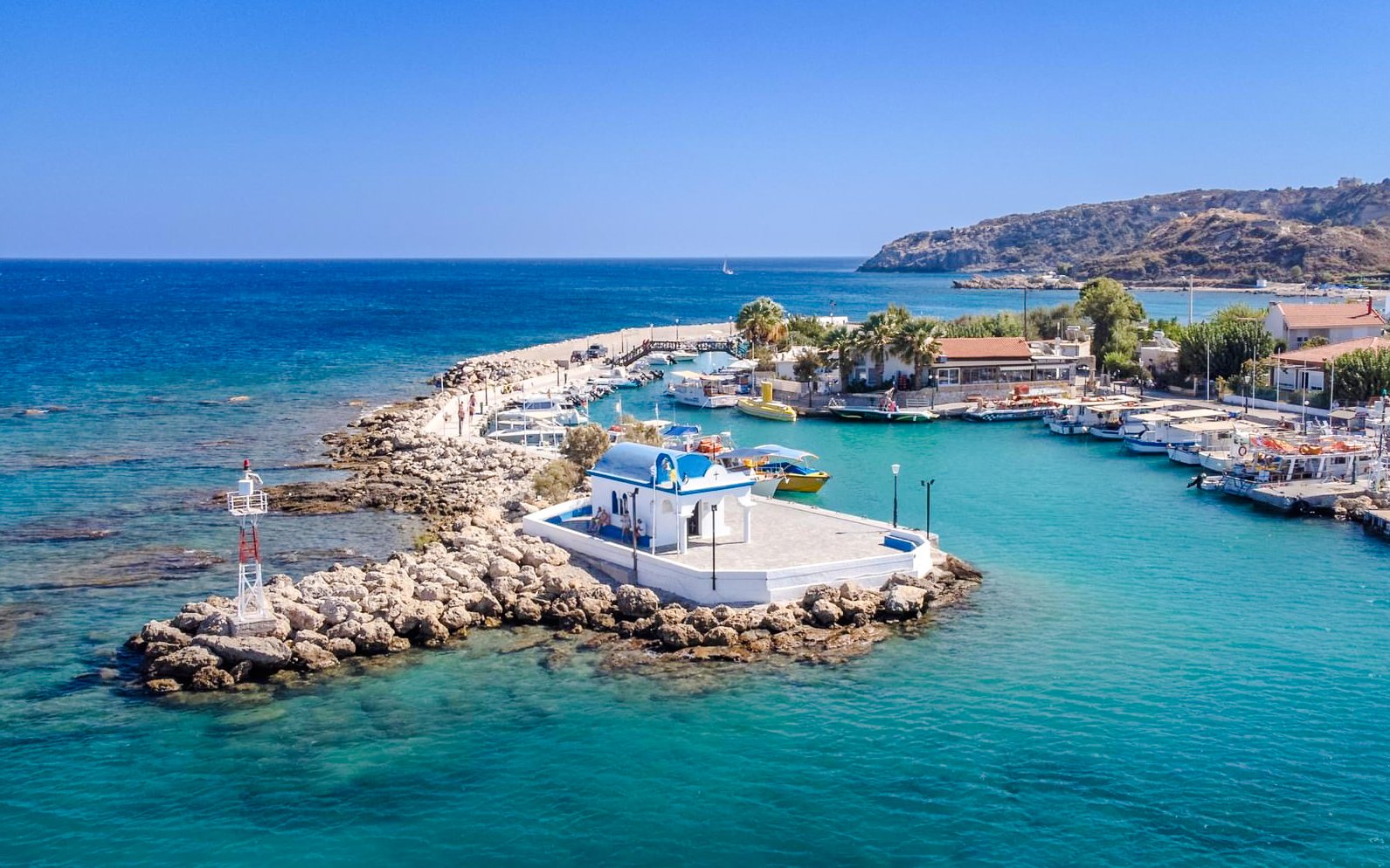 Afandou Bay with boats docked near a small chapel, Rhodes cruise.