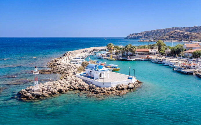 Afandou Bay with boats docked near a small chapel, Rhodes cruise.