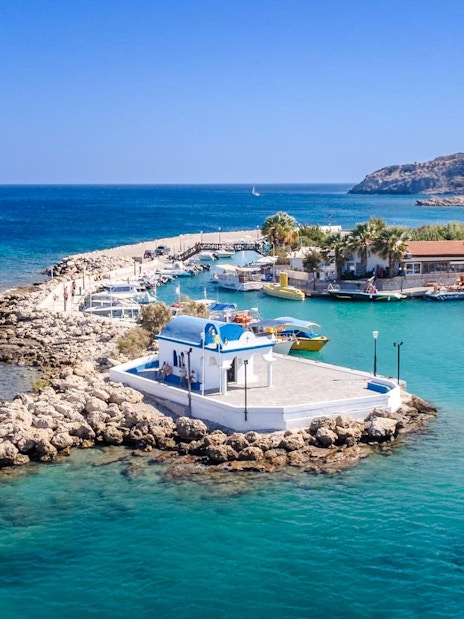 Afandou Bay with boats docked near a small chapel, Rhodes cruise.