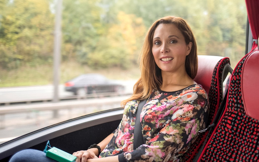 Person enjoying a scenic bus ride on the Stratford, Oxford, Cotswolds & Warwick Castle Tour.