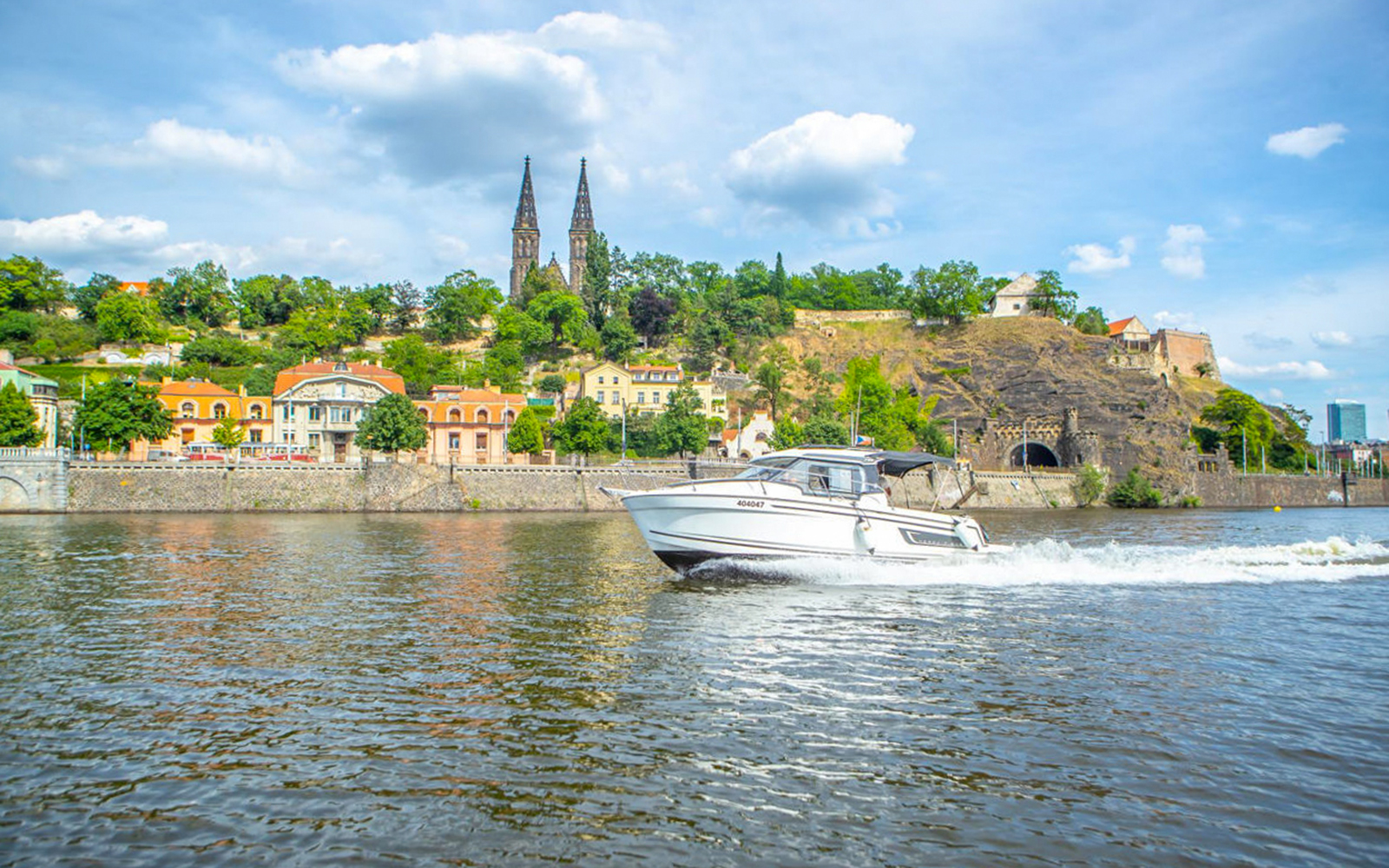 Yacht cruising on Vltava River with Vyšehrad Castle in Prague.