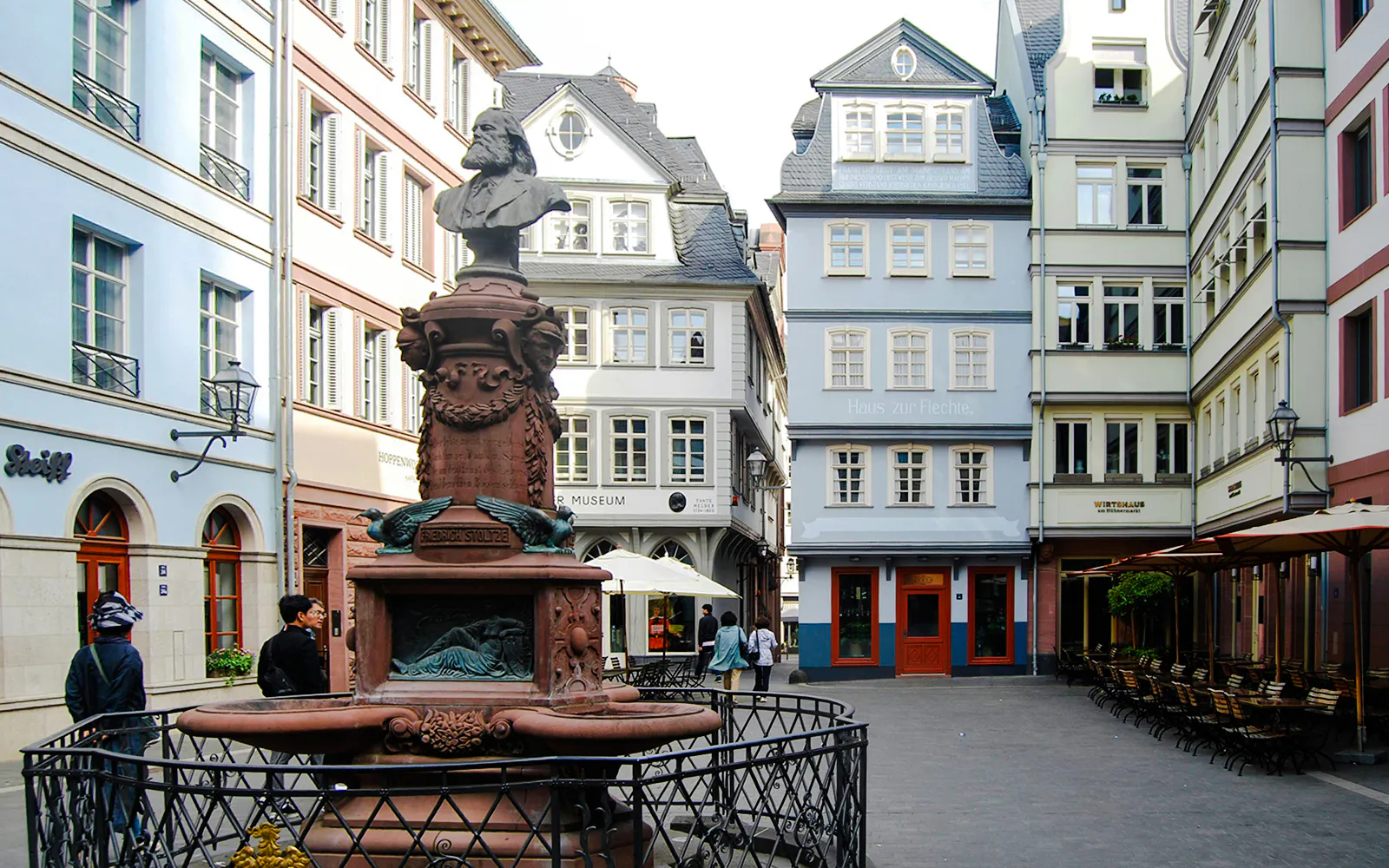 Stoltze-Brunnen fountain in a historic square, Frankfurt, surrounded by traditional buildings.
