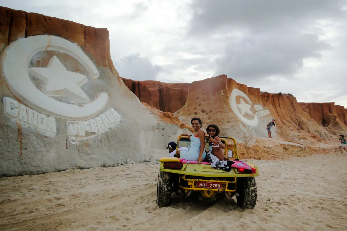 Dune buggy ride at Canoa Quebrada cliffs, Sao Paulo, with carved star and crescent symbol.