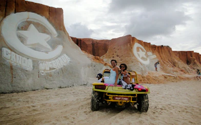 Dune buggy ride at Canoa Quebrada cliffs, Sao Paulo, with carved star and crescent symbol.