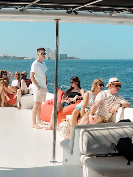 Tourists relaxing on a luxury yacht cruise with city skyline in the background.
