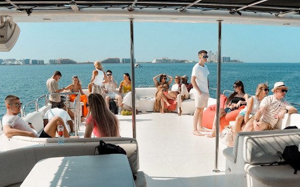 Tourists relaxing on a luxury yacht cruise with city skyline in the background.