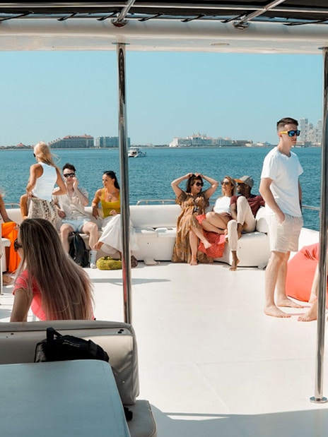 Tourists relaxing on a luxury yacht cruise with city skyline in the background.