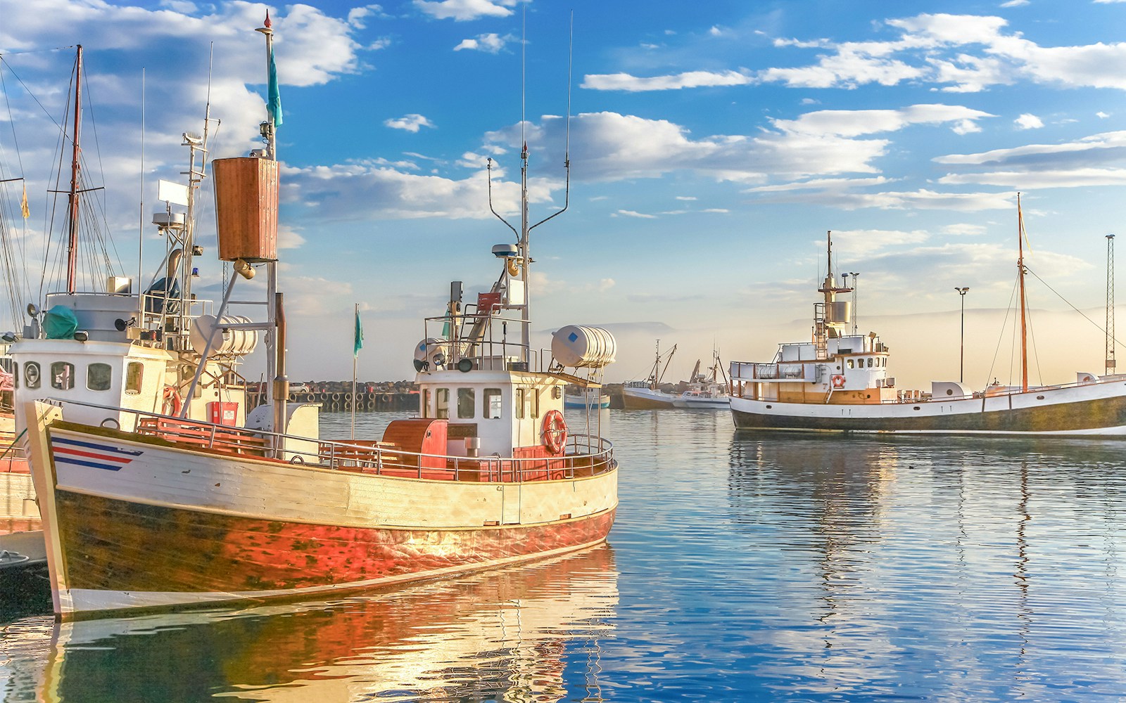 Traditional old fisherman boats lying in harbor in beautiful golden evening light at sunset, Iceland, northern Europe