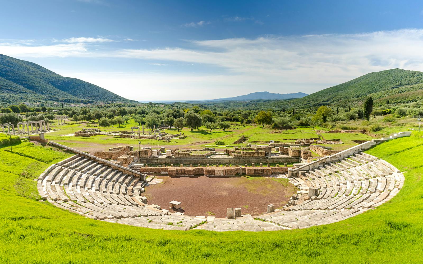 Ancient Messene theater ruins surrounded by green hills, Peloponnese, Greece.