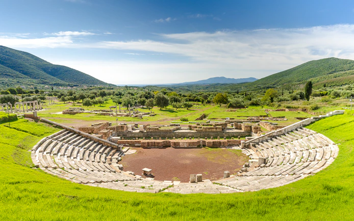 Ancient Messene theater ruins surrounded by green hills, Peloponnese, Greece.