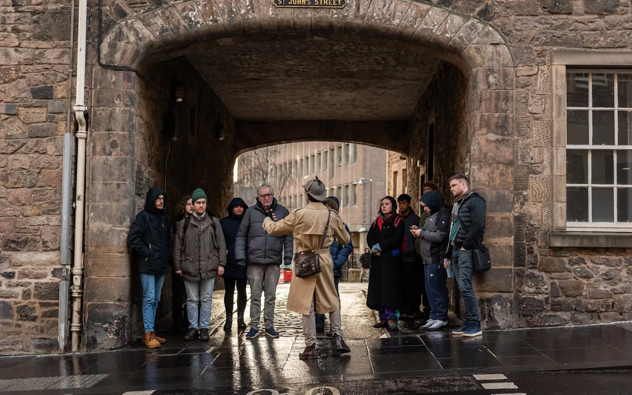 Tour group listening to a guide on St. John's Street, Edinburgh, during a historical gems tour.