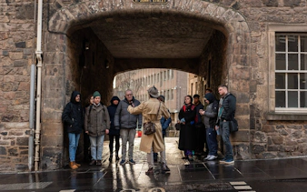 Tour group listening to a guide on St. John's Street, Edinburgh, during a historical gems tour.