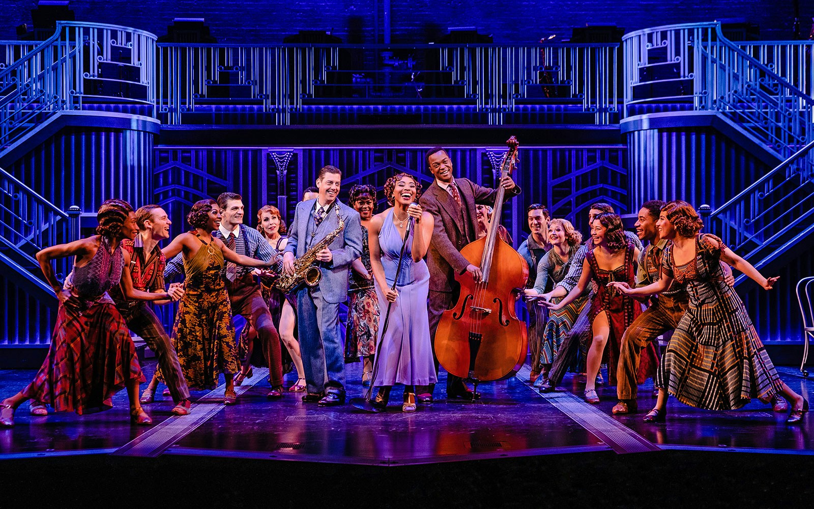 Musical cast performing "Some Like it Hot" on stage with saxophone and double bass.