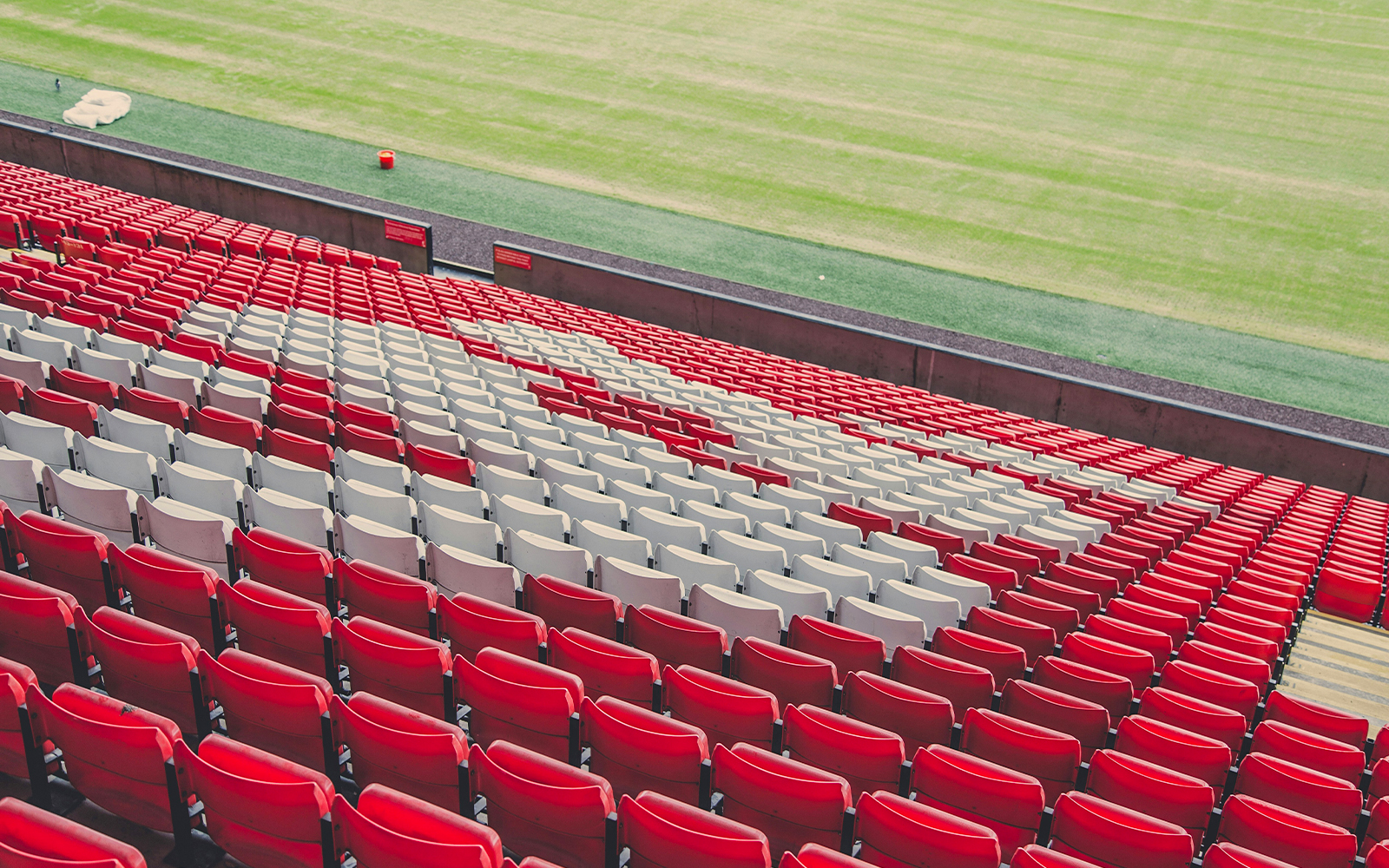Liverpool football stadium red and white seats overlooking the pitch.