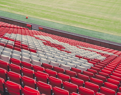 Liverpool football stadium red and white seats overlooking the pitch.