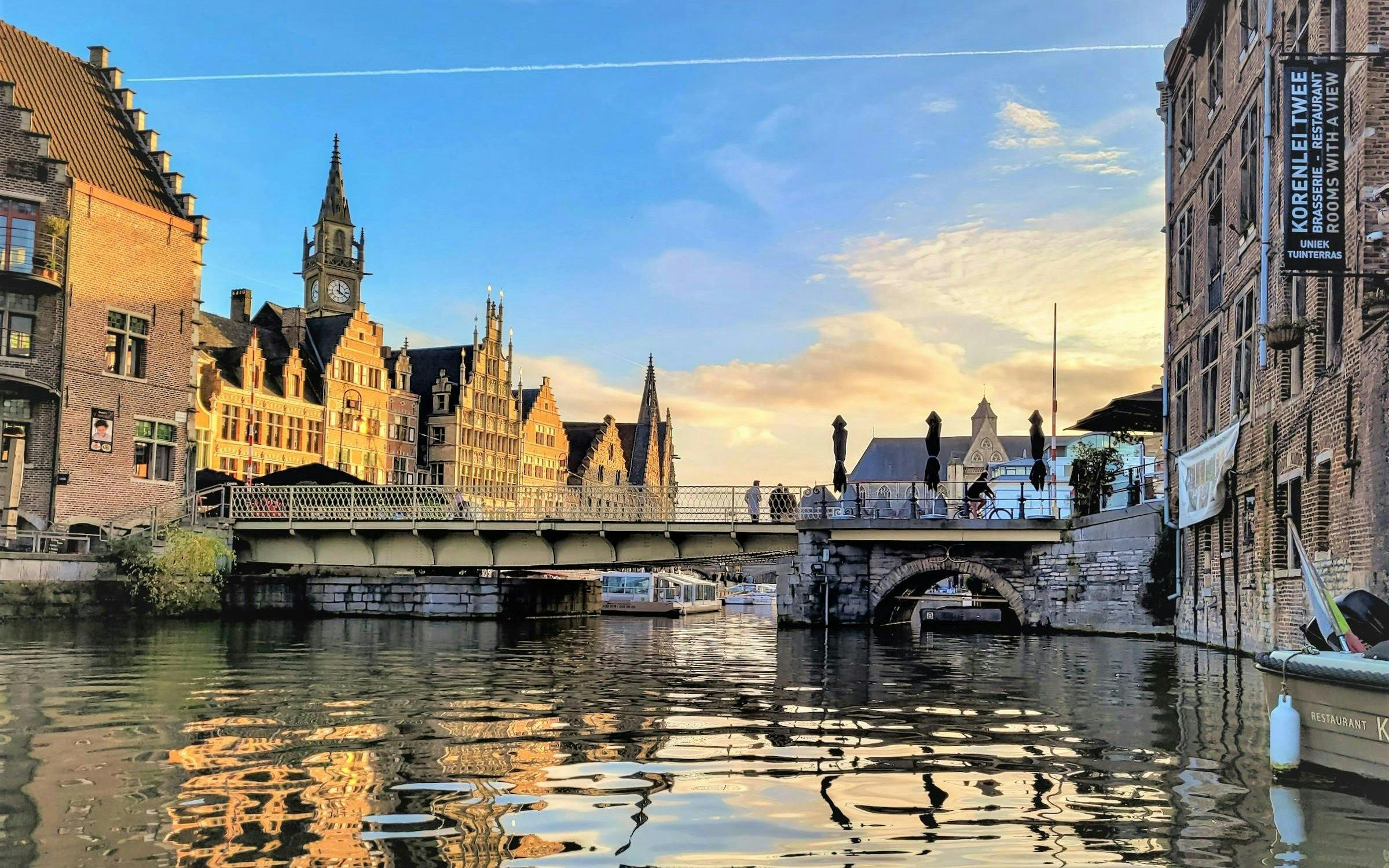 Bruges canal view with historic buildings and bridge at sunset.