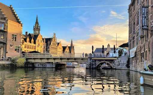 Bruges canal view with historic buildings and bridge at sunset.