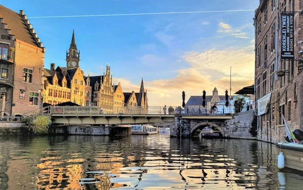 Bruges canal view with historic buildings and bridge at sunset.
