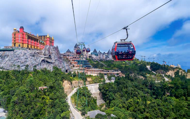 Cable car ascending to Ba Na Hills with scenic view of lush landscape and hilltop buildings.