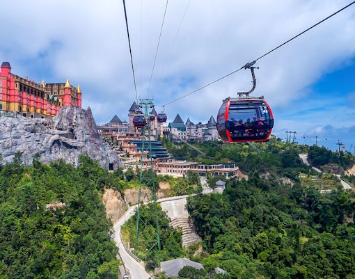 Cable car ascending Ba Na Hills with lush greenery and distant mountains in Da Nang, Vietnam.