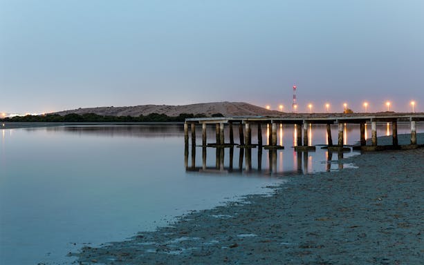 Pier at dusk by a calm shoreline, ideal for crab hunting tours.