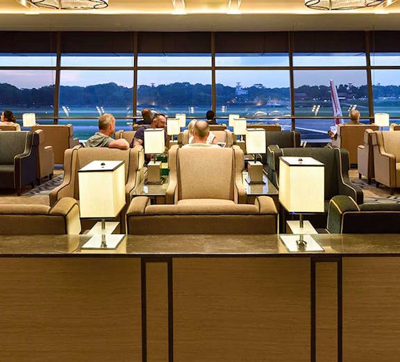 Plaza Premium Lounge Singapore with seating and view of airport runway.