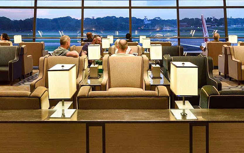 Plaza Premium Lounge Singapore with seating and view of airport runway.