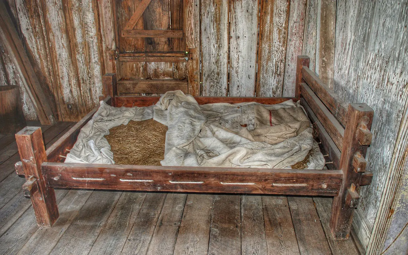 Wooden bed with straw mattress in a cabin at Whitney Plantation, New Orleans tour.