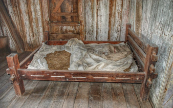 Wooden bed with straw mattress in a cabin at Whitney Plantation, New Orleans tour.