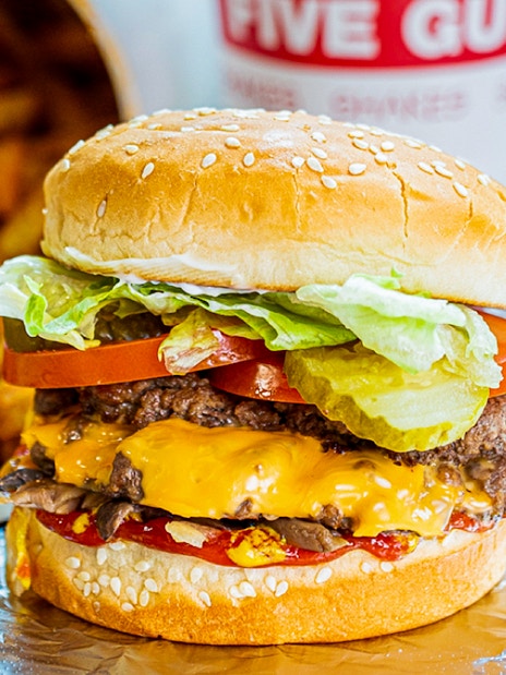 Burger with cheese, lettuce, tomato, and pickles, served with fries at Five Guys, Dubai Marina.