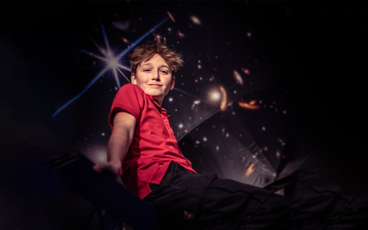 Child enjoying The TUBE experience in Copenhagen with a cosmic backdrop.