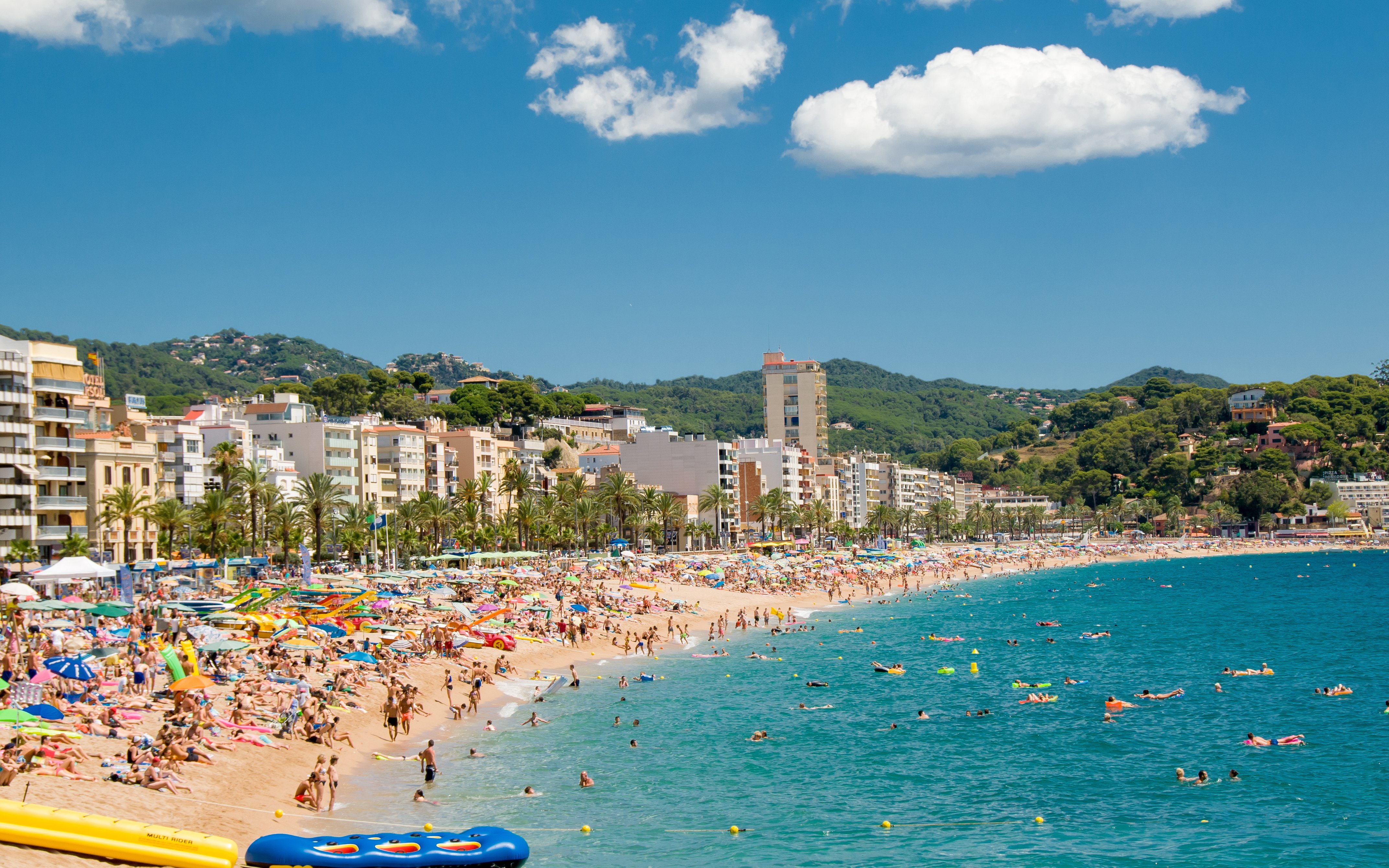 Lloret de Mar beach crowded with sunbathers and swimmers, Costa Brava coastline.