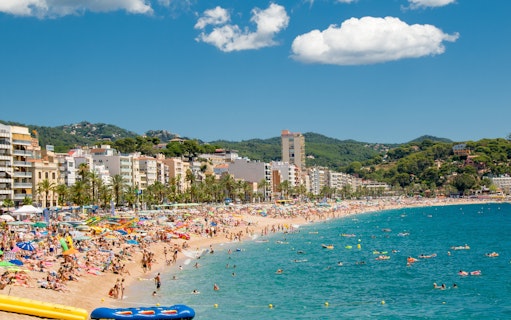 Lloret de Mar beach crowded with sunbathers and swimmers, Costa Brava coastline.