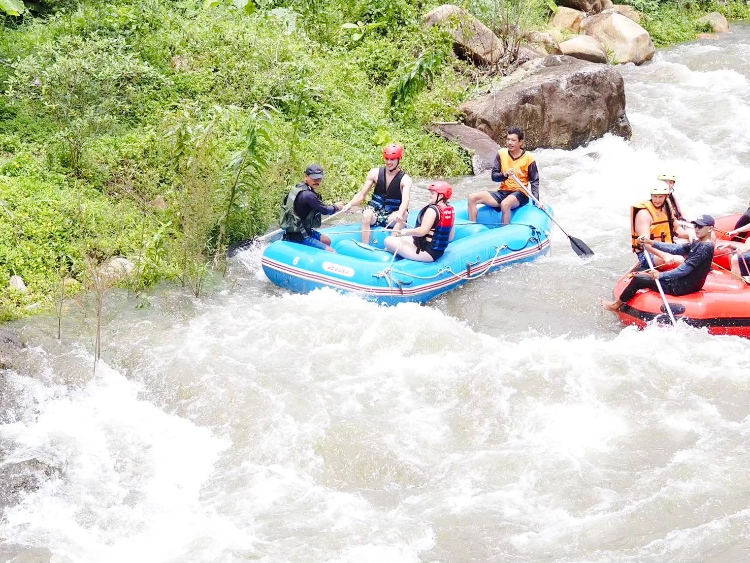 White water rafting on a river in Krabi with lush greenery and rocky terrain.