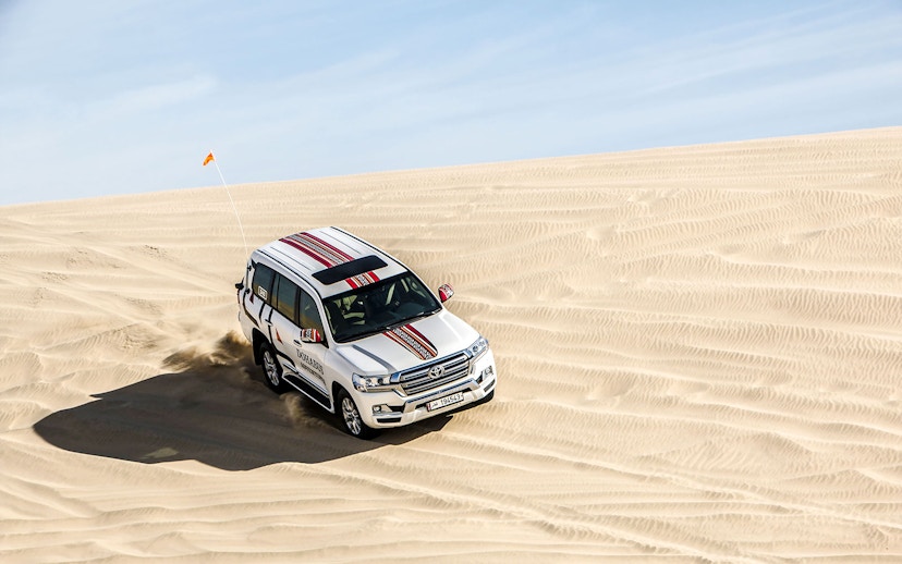 SUV driving on sand dunes during a desert safari in Doha.