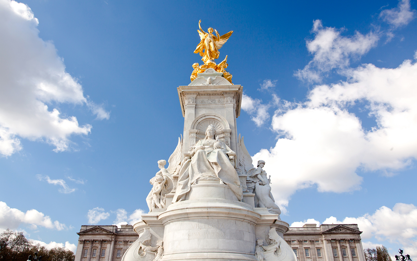 Buckingham Palace Memorial with Queen Victoria statue under a blue sky.