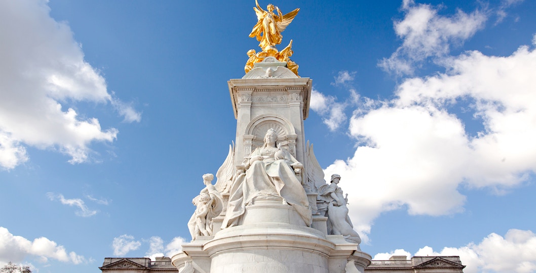 Buckingham Palace Memorial with Queen Victoria statue under a blue sky.