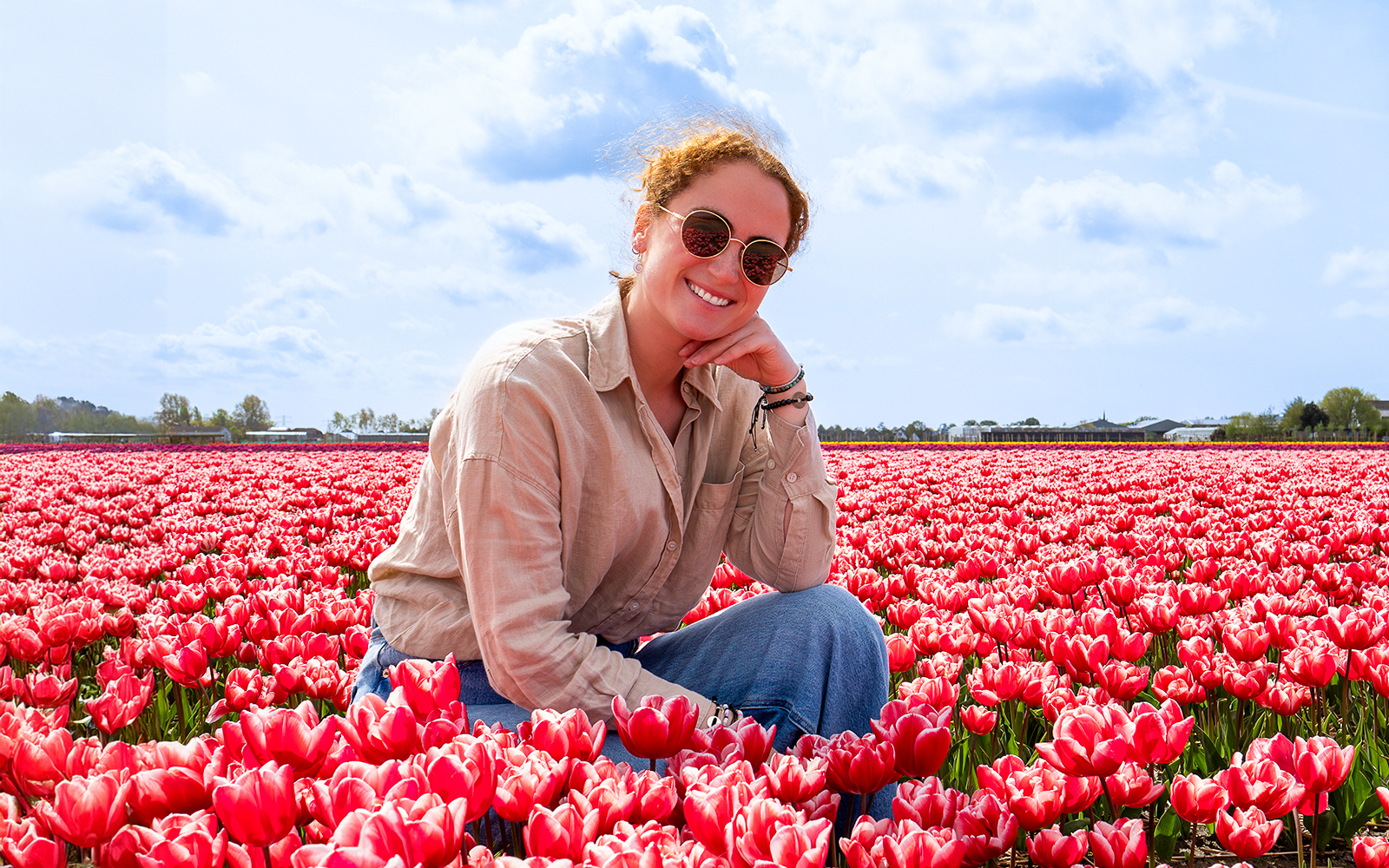 Woman sitting among red tulips at Tulip Barn, Netherlands.