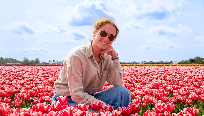 Woman sitting among red tulips at Tulip Barn, Netherlands.