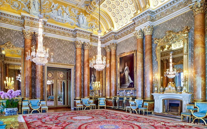 Blue Drawing Room at Buckingham Palace with chandeliers, ornate columns, and regal portraits.