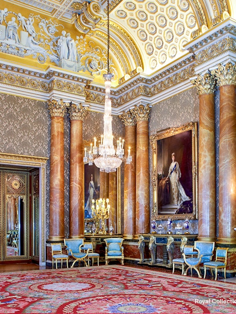 Blue Drawing Room at Buckingham Palace with chandeliers, ornate columns, and regal portraits.